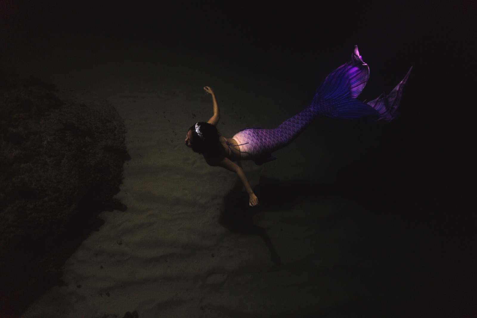 A night mermaid dive, light falling from the surface